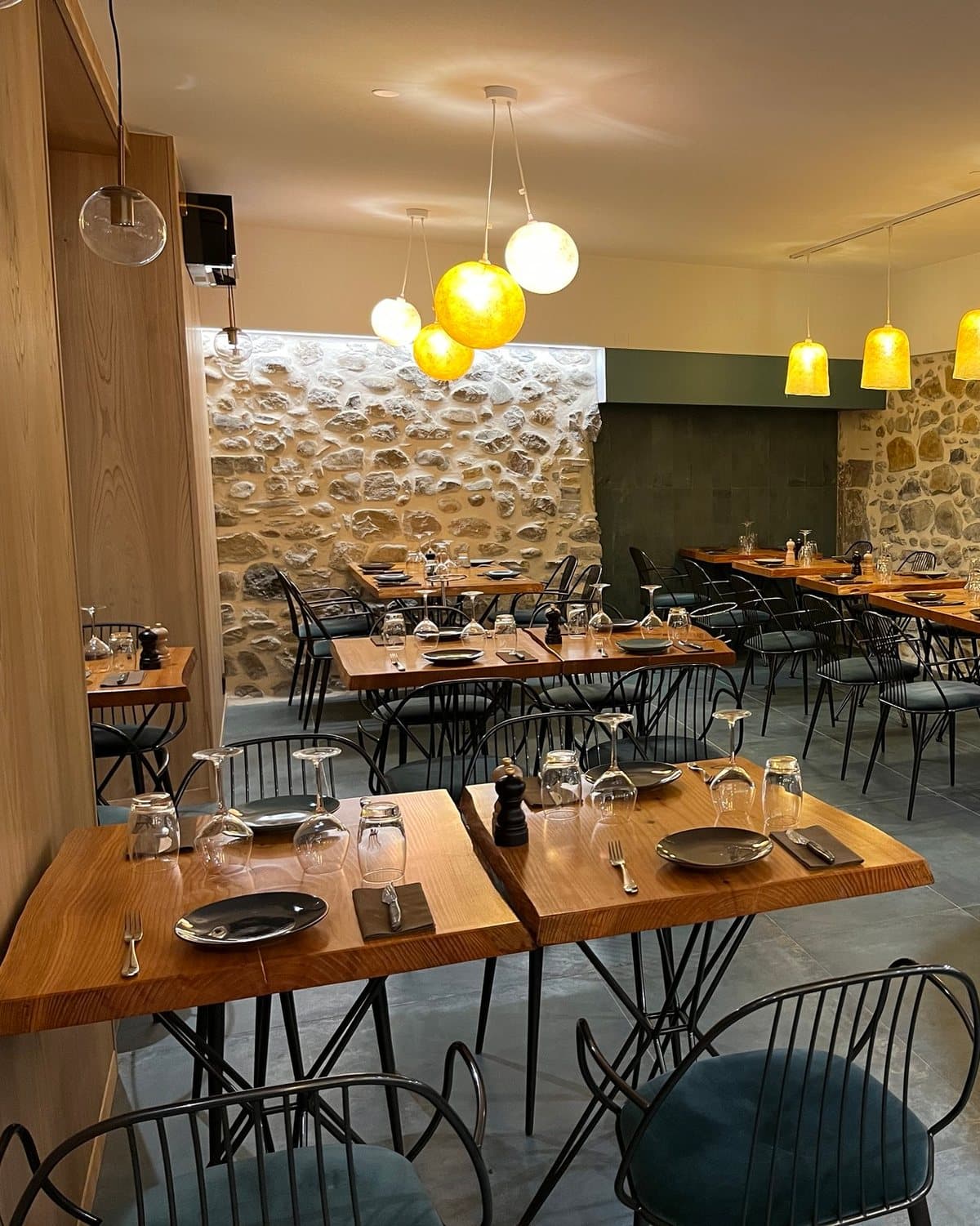 Salle du restaurant Le Commerce : pierre apparente, bois clair et suspensions lumineuses