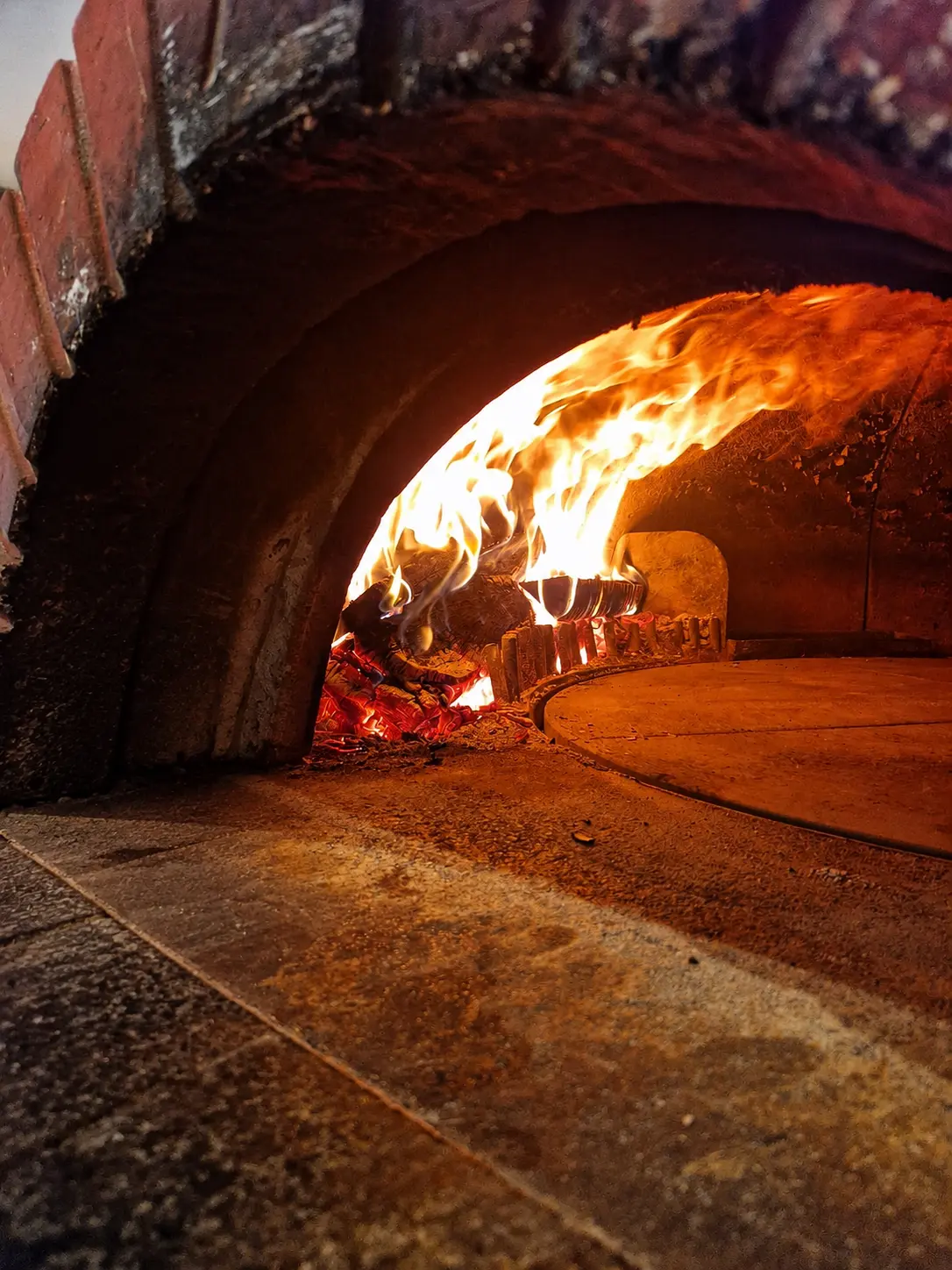 Flammes dansant dans le four à bois du restaurant Le Commerce